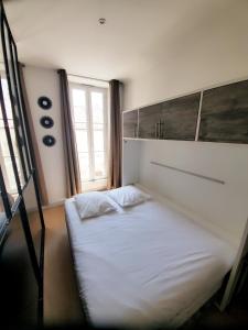 een wit bed in een kamer met een raam bij L'ORATOIRE 2 in La Rochelle