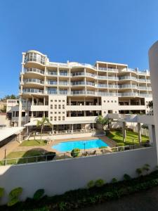 a large white apartment building with a swimming pool at Santorini, Margate in Margate