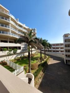 einen Balkon mit Palmen und ein Gebäude in der Unterkunft Santorini, Margate in Margate