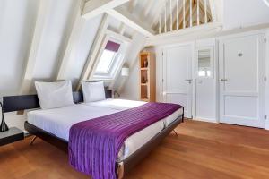 een slaapkamer met een groot bed en een paarse deken bij City-centre, Canal-house, luxurious , stylish bedroom, ensuite bathroom, own entrance in Amsterdam
