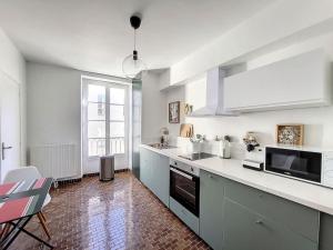 una grande cucina con banconi bianchi e una grande finestra di Le TouCan - 100m Palais et Pont ad Avignone Altre 24 foto