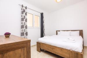 a bedroom with a white bed and a wooden table at Contessa Caterina in Karousádes