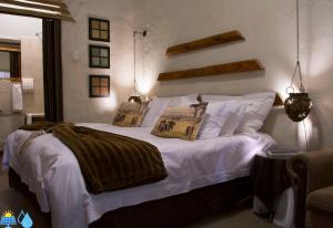 um quarto com uma cama com lençóis brancos e almofadas em Riverbush Lodge Guesthouse em Parys