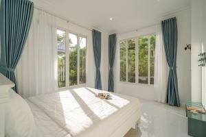een slaapkamer met een groot bed en blauwe gordijnen bij Casa Villa - Ocean View - Sealinks City Resort in Phan Thiet