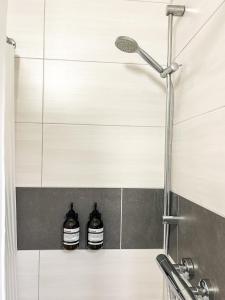 - une douche avec 2 bouteilles assises sur une étagère dans la salle de bains dans l'établissement Modernes Apartment in Diepholz, à Diepholz