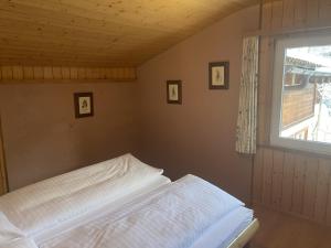 Bett in einem Zimmer mit Fenster in der Unterkunft Chalet Hotel Adler AG in Kandersteg