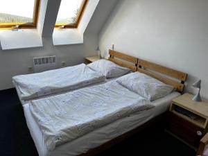 a bedroom with a bed with white sheets and two windows at Hotel Figura in Malá Morávka