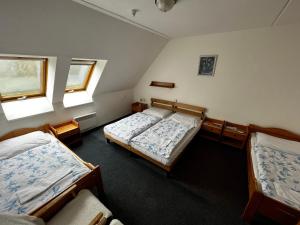 a bedroom with two beds and two windows at Hotel Figura in Malá Morávka