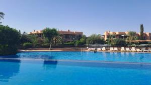 una gran piscina azul con sillas y edificios blancos en AbirKech appartement en Marrakech