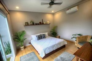 una camera da letto con un letto con piante e un ventilatore a soffitto di Beautiful Modern Garden Home a Kampot