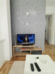 un soggiorno con TV e orologio a parete di JOKER Apartman a Požarevac 1 altra foto