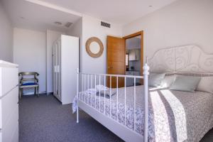 a bedroom with a white bed and a chair at Casa Xanadu Carmona - Stylish villa with rooftop terrace and stunning views of Parador in Carmona