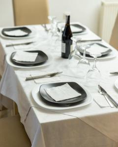 Jusaj Hotel Glob في بيخا: طاولة بيضاء مع أطباق سوداء واكواب للنبيذ