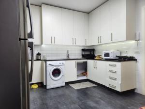 a kitchen with white cabinets and a washing machine at Charming 2BR Gemayze in Beirut