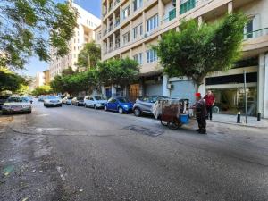 Charming 2BR Gemayze في بيروت: رجل يدفع عربة أسفل شارع المدينة