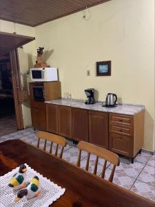 uma cozinha com uma mesa e um balcão com um micro-ondas em Casa Família Mattos em Xangri-lá