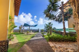 a walkway in front of a building with palm trees at Praia Sol Hotel - Leme Hotel Ltda in Serra
