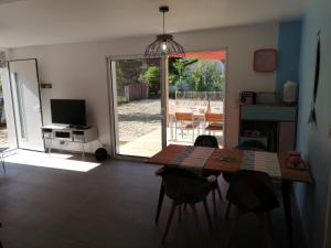 ein Wohnzimmer mit einem Esstisch und einer Glasschiebetür in der Unterkunft VILLA HÉLIOS in Jard-sur-Mer