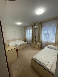 a bedroom with two beds and two windows at Hotel Ada - Otoka in Sarajevo