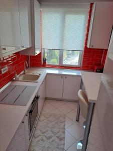 een keuken met witte kasten en rode tegels bij Rosso Apartment in Braşov