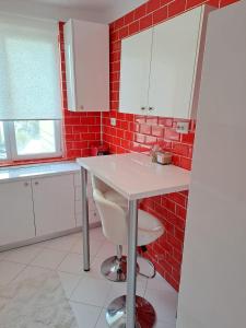 een keuken met een wit aanrecht en een rode bakstenen muur bij Rosso Apartment in Braşov