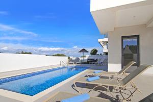 a villa with a swimming pool and lounge chairs at Villa Genesis in Protaras