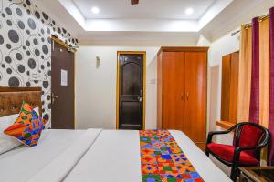 a bedroom with a bed and a red chair at FabHotel Sagar Royale in Bhubaneshwar