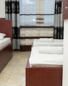 two beds in a room with a window at Jusaj Hotel Glob in Peje