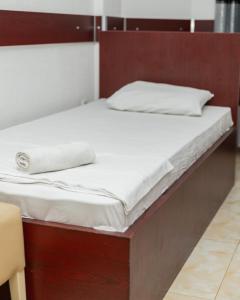 Jusaj Hotel Glob في بيخا: سرير بملاءات بيضاء وإطار سرير خشبي