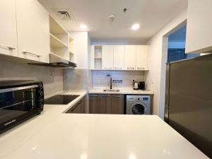 a white kitchen with a sink and a dishwasher at Desert Flower Delight in Al Qurayyah