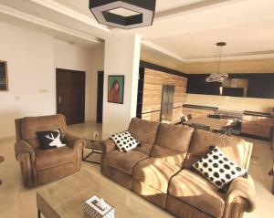 a living room with two couches and a kitchen at 3 Bedroom mountain view apartment overlooking Al Fuhais in Amman