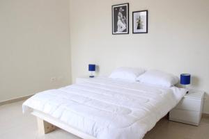 een witte slaapkamer met een groot wit bed met witte lakens bij Modern 3BR Apt next to Hotel Dieu in Beiroet