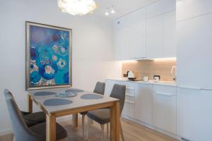 een keuken met een tafel en stoelen en een schilderij bij Apartament Premium PINEA 203 in Pobierowo