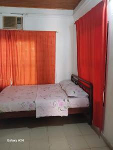 1 dormitorio con 2 camas y cortina roja en Hospedaje Eden, en Los Naranjos