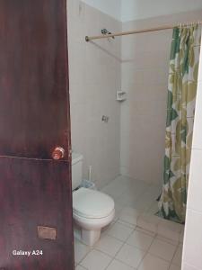 a bathroom with a toilet and a shower curtain at Hospedaje Eden in Los Naranjos