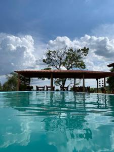 a swimming pool with a pergola and blue water at Sítio Barriguda in Alexânia