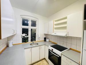 a kitchen with white cabinets and a sink and a window at aday - Sunset Suite in Randers