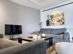 een woonkamer met 2 banken en een flatscreen-tv bij Chic Contemporary 3BR in Mar Mikhael in Beiroet