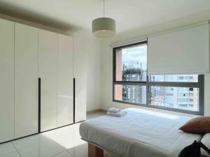 een slaapkamer met een bed en een groot raam bij Modern 3BR Apt next to Hotel Dieu in Beiroet