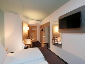 a hotel room with a bed and a flat screen tv at B&B Hotel Berlin-Dreilinden in Kleinmachnow