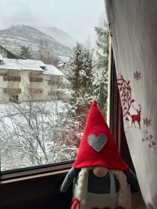 um bicho de peluche com um chapéu vermelho a olhar pela janela em Gina's Home - Appartamento nel cuore di Bardonecchia em Bardonecchia