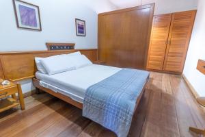 Praia Sol Hotel by Castelo Itaipava في سيرا: غرفة نوم بسرير وخزانة خشبية