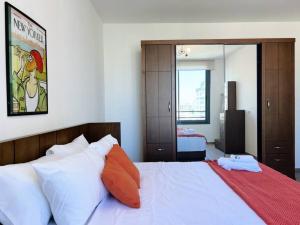 ein Schlafzimmer mit einem großen Bett mit weißer Bettwäsche und orangefarbenen Kissen in der Unterkunft Elevated 2BR living in Hamra in Beirut