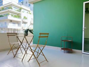 a table and chairs in a room with a green wall at Chill 2Br haven Gemmayze in Beirut