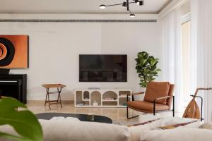 ベイルートにあるStunning Artist House in Saifiのソファと壁掛けテレビのあるリビングルーム