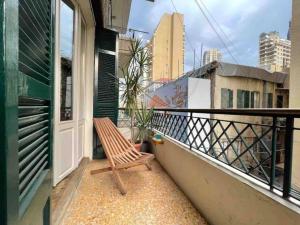 un banc en bois assis sur un balcon avec vue dans l'établissement Designer 1BR apt in Gemmayze, à Beyrouth