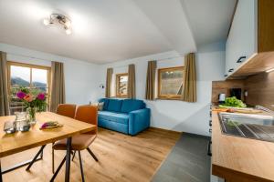 een keuken en een woonkamer met een blauwe bank bij Pardellerhof Appartment Runcada in Luson