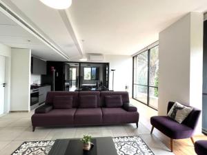 a living room with a purple couch and a kitchen at Pleasant 1BR apt with green views - Jamhour in Rujūm