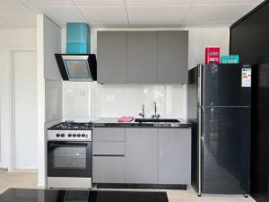 uma cozinha com armários brancos e um frigorífico preto em Pleasant 1BR apt with green views - Jamhour em Rujūm