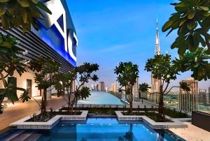 a view of a building with a swimming pool and palm trees at Skyline Serenity 2BR Haven in Dubai